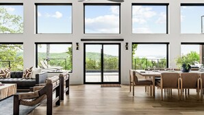 Une pièce spacieuse dotée de grandes fenêtres, d’un coin repas et d’un espace salon offrant une vue sur l’extérieur.