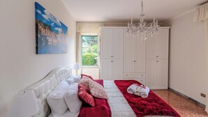 A bedroom with a bed, a chandelier, a wardrobe, and a painting on the wall. - Casa Marino (Ciampino)