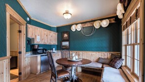 A cozy cabin-style room with a wooden dining table, a bench, and a bed by the window. - Cabin 3 at the Almo Inn, Close to City of Rocks National Park and Castle Rock (Almo)