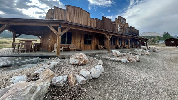 A rustic wooden building with a covered patio area, large windows, and a view of the surrounding landscape. - Cabin 3 at the Almo Inn, Close to City of Rocks National Park and Castle Rock (Almo)