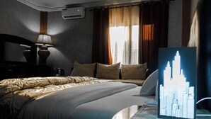 Una habitación de hotel con una cama, una mesita de noche, una lámpara y una obra de arte con un paisaje urbano en la pared.
