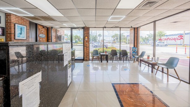 A restaurant interior with a counter, seating area, and large windows. - Oyo Hotel Bartow (Bartow)
