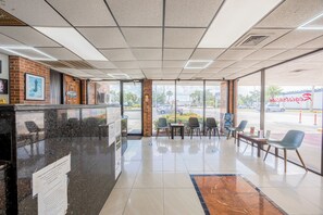 L’intérieur d’un restaurant, avec un comptoir, un espace pour les clients et de grandes fenêtres.