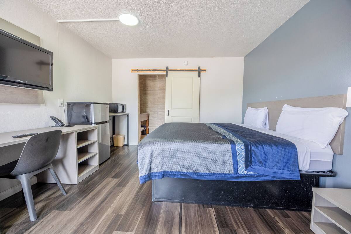 Ein Hotelzimmer mit Bett, Schreibtisch mit Stuhl, Fernseher und Mikrowelle.