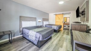 A hotel room with two beds, a desk, a chair, a TV, and a wooden door. - Oyo Hotel Bartow (Bartow)