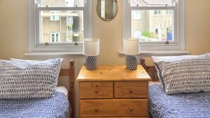 Une chambre avec deux lits, une commode en bois et deux lampes de chevet.