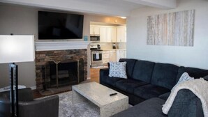 A living room with a fireplace, a sofa, a coffee table, and a TV. - Spacious Vermilion House on the Lake (Vermilion)