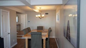 A dining area with a wooden table and four chairs, a chandelier, and a framed artwork on the wall. - Spacious Vermilion House on the Lake (Vermilion)