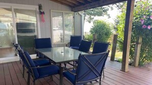 A covered patio with a glass table and blue chairs. - Spacious Vermilion House on the Lake (Vermilion)