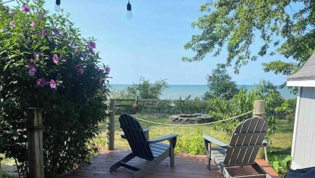 A wooden deck with two Adirondack chairs facing a view of the ocean. - Spacious Vermilion House on the Lake (Vermilion)