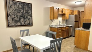A kitchen with wooden cabinets, a white countertop, and a dining table with chairs.
