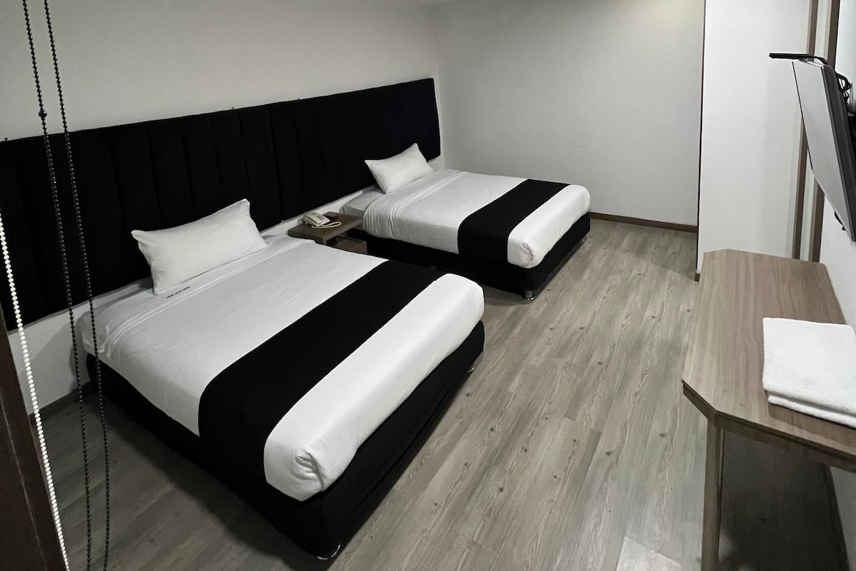 Ein Hotelzimmer mit zwei Betten, einem Schreibtisch und einem Hängesessel.