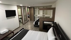Een hotelkamer met een groot bed, een bureau, een televisie en een garderobe.
