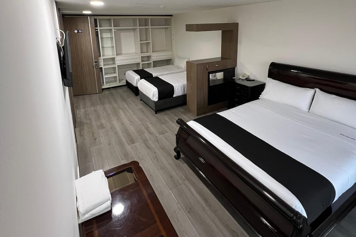 Ein Hotelzimmer mit einem großen Bett, einem kleineren Bett, einem Schreibtisch und einem Kleiderschrank.