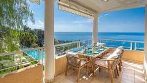 A terrace with a table and chairs, overlooking a pool and a scenic view of the sea. - Magnificent sea view villa - DG (Cap-d'Ail)