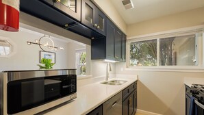 Una cocina moderna con electrodomésticos de acero inoxidable, armarios oscuros y una encimera blanca.
