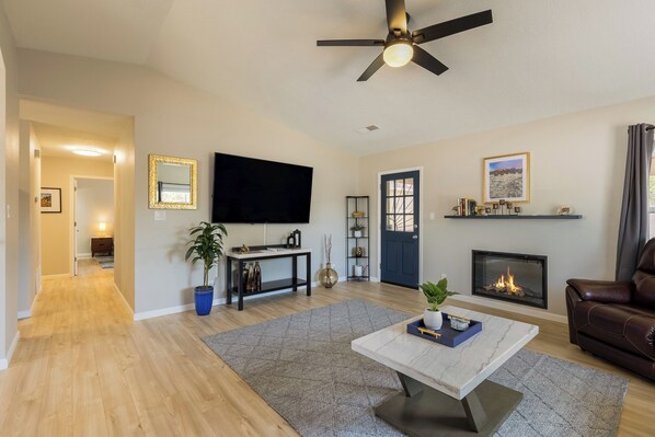 Una sala de estar con chimenea, televisor y ventilador de techo.