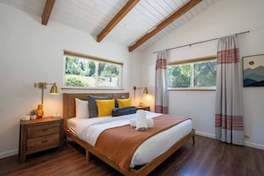 Quarto com cama de madeira, duas mesas de cabeceira e janela com cortinas.