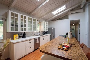Una cucina moderna con mobili bianchi, un'isola in legno e vista sull'esterno.