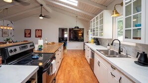 A kitchen with a central island, wooden flooring, white cabinetry, and a skylight.