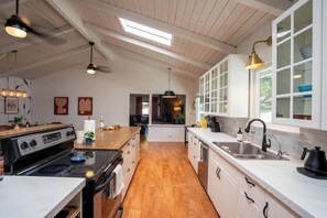 Una cucina con isola centrale, pavimento in legno, mobili bianchi e un lucernario.
