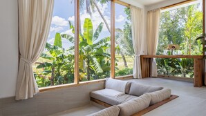 A room with a large window, a sofa, and a wooden bench. - Luxurious 2BR Villa - Scenic Rice Field Views - Beautiful Swimming Pool & Garden (Canggu)