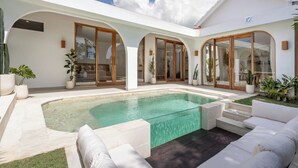 A modern house with a swimming pool, outdoor seating, and large glass doors. - Luxurious 2BR Villa - Scenic Rice Field Views - Beautiful Swimming Pool & Garden (Canggu)