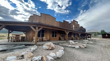 Guests can enjoy a welcoming porch with benches and tables, surrounded by large windows and a flat roof.