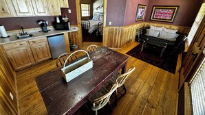 Une cuisine compacte avec des meubles en bois, une table à manger et un petit coin salon comprenant un canapé et des fauteuils.