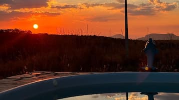 A sunset with clouds reflected in a body of water, a utility pole, and a fire hydrant.