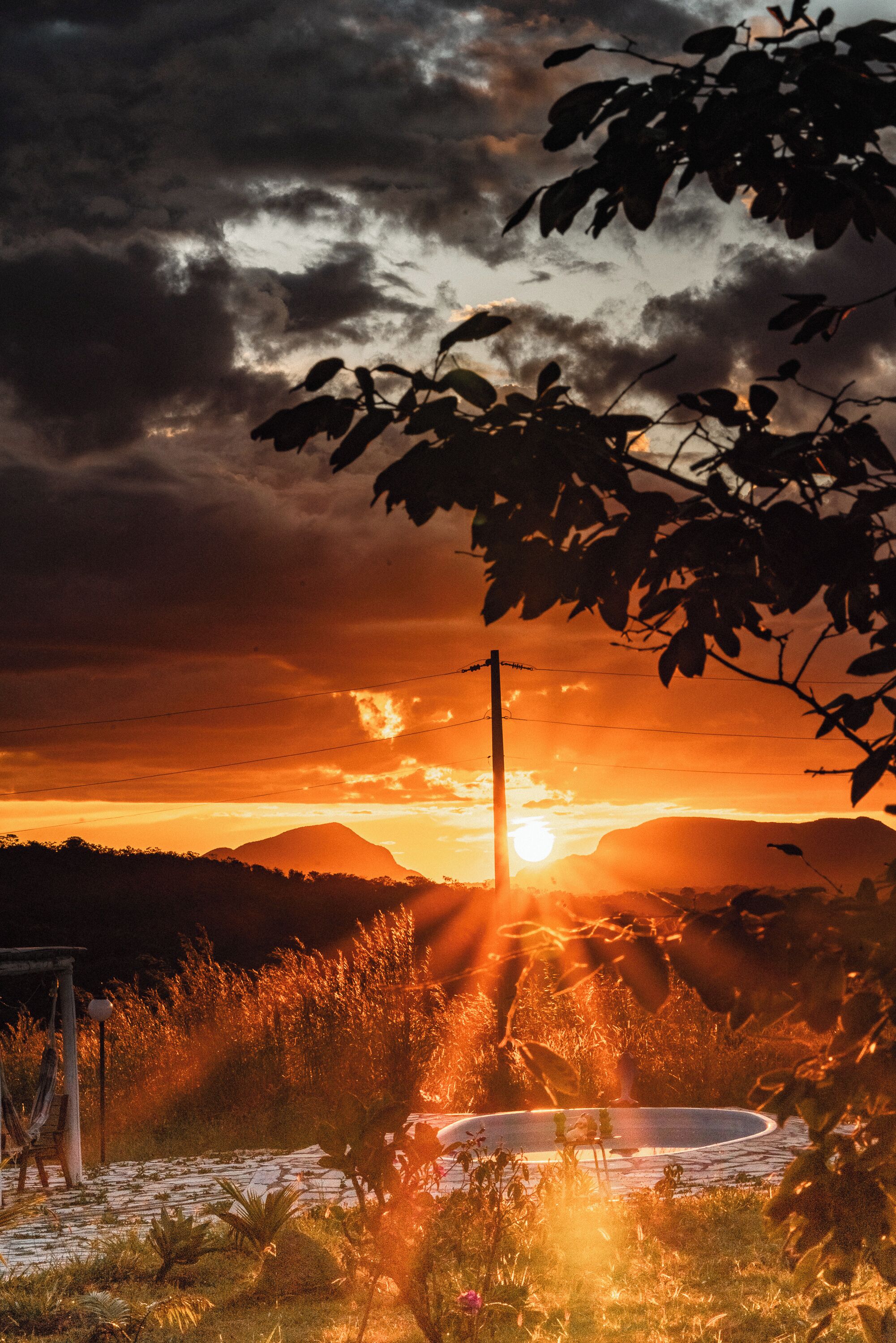A sunset over a mountainous landscape with a body of water in the foreground.