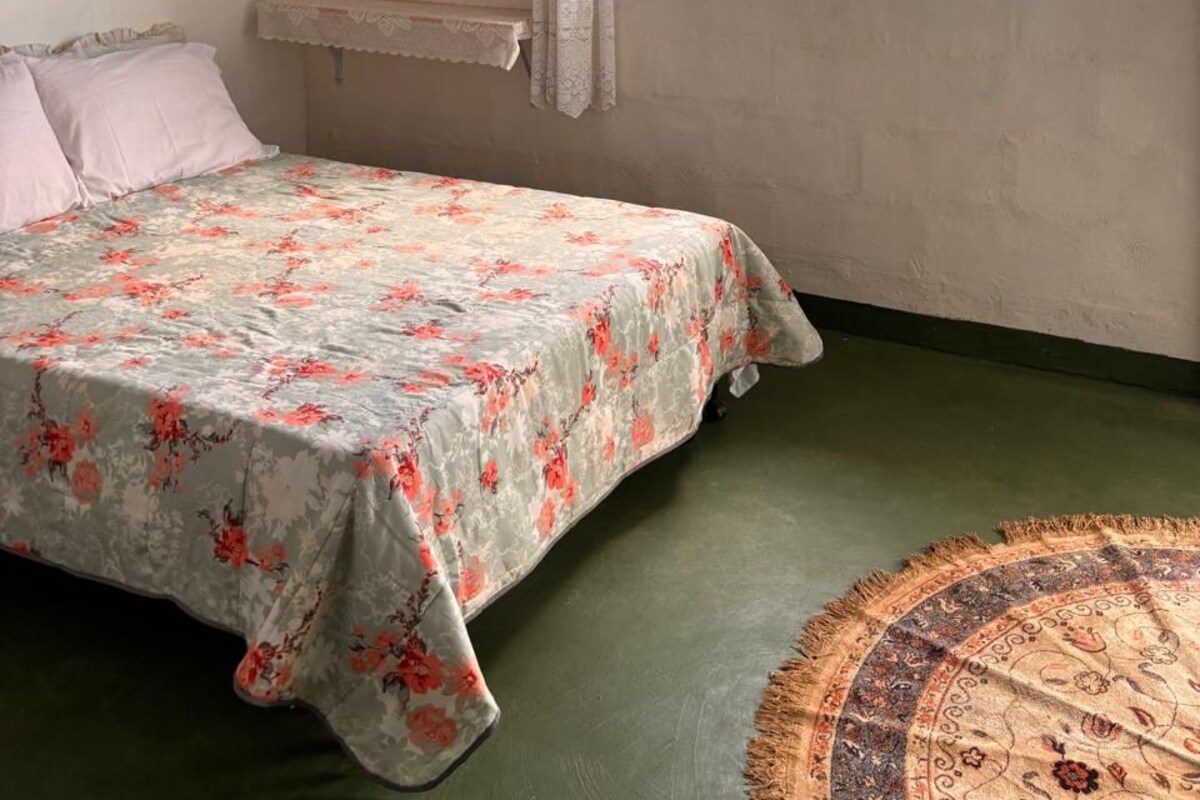 Ein Zimmer mit einem Bett, einem Fenster und einem an der Wand befestigten Regal.