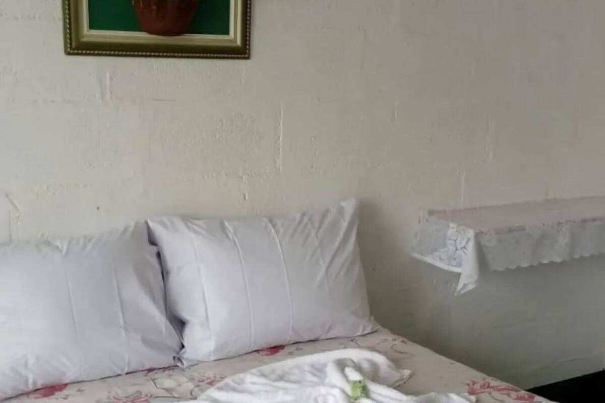 A hotel room with a bed, pillows, a floral bedspread, and a towel arranged on the bed.