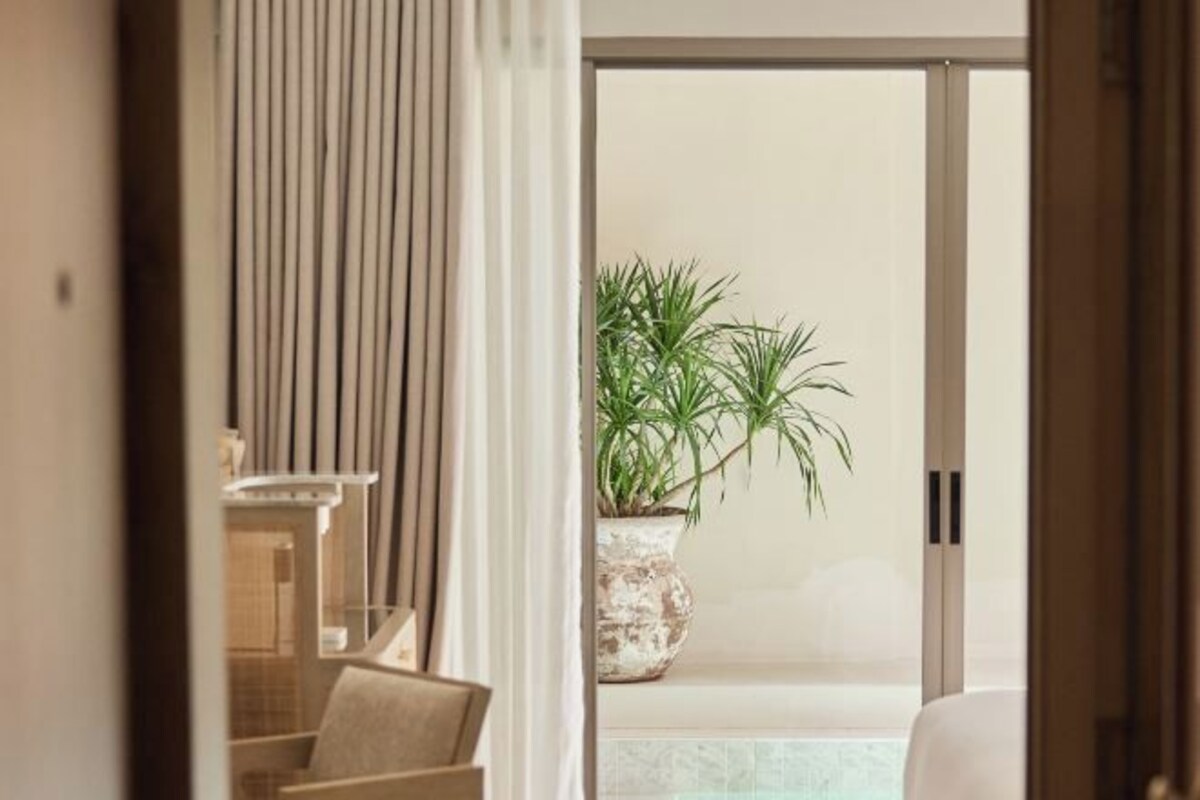 Una habitación de hotel con un puerta corredera de cristal que da a un balcón con una maceta.