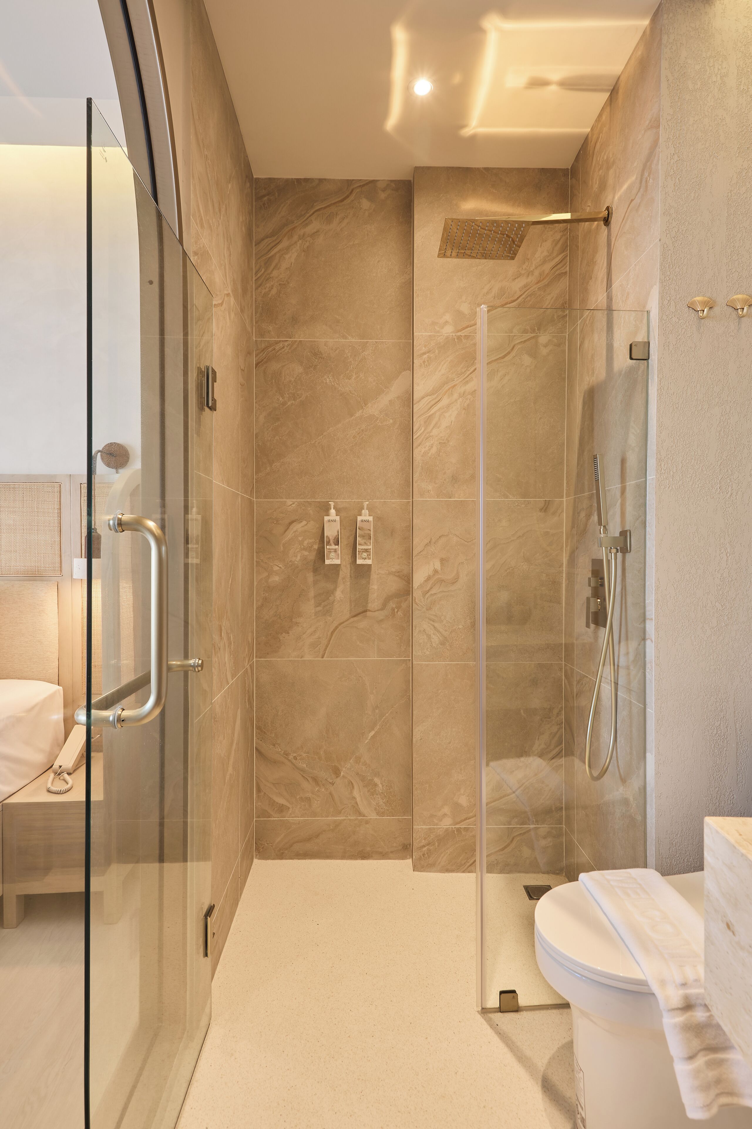 Een moderne badkamer met een glazen douchecabine, toilet en een wastafel met een handdoek.