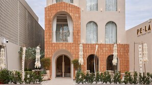 Un hotel con fachada moderna, amplias ventanas arqueadas y un letrero que dice "PE-LA HOTEL".