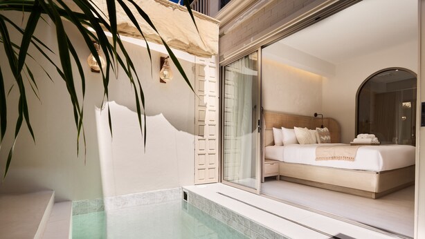 Un dormitorio moderno con una cama grande, cabina de ducha de vidrio y vistas a la ciudad.