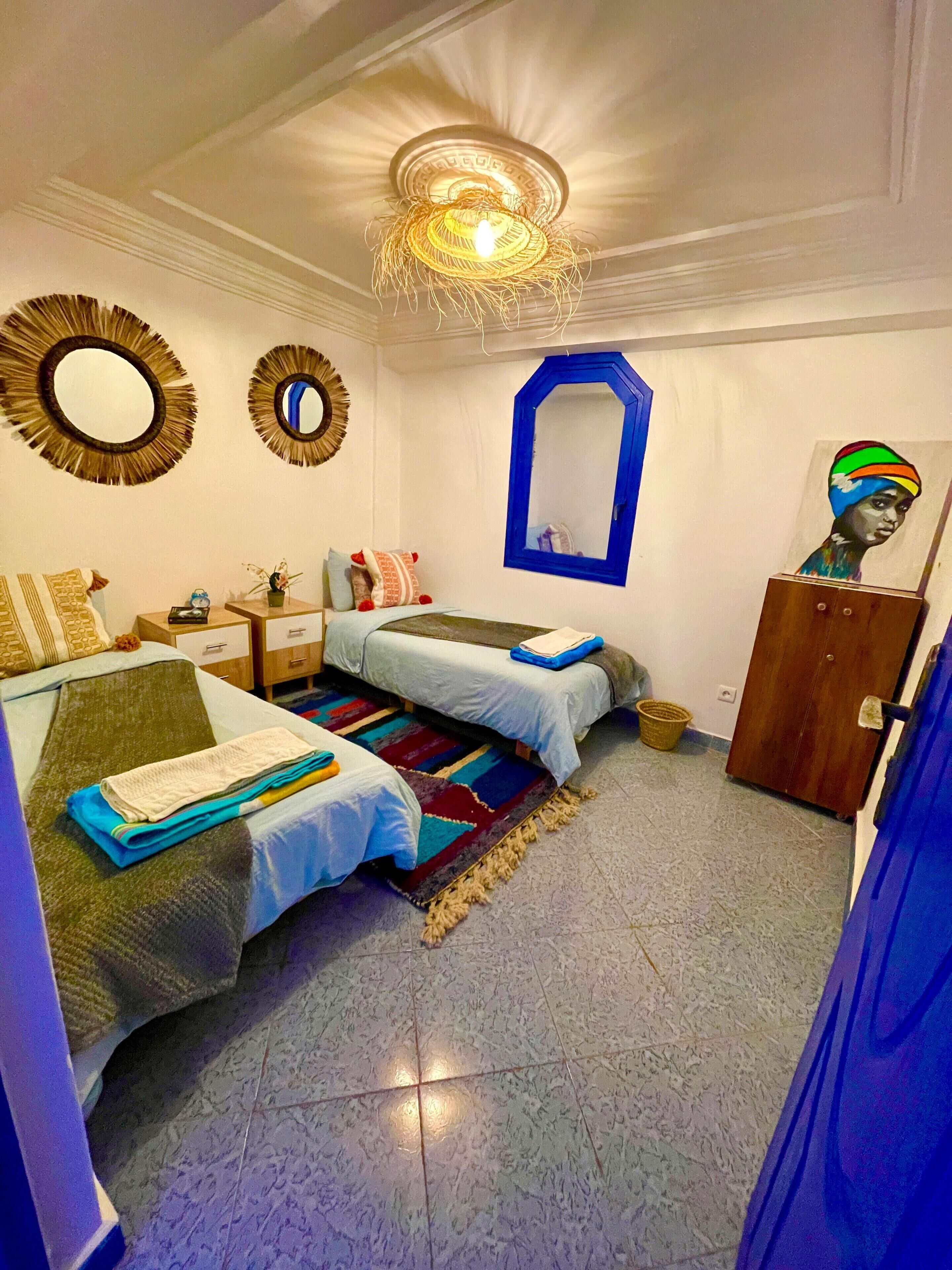 A bedroom with two beds, a dresser, a mirror, and a ceiling light fixture.