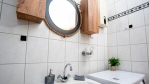 A bathroom with a white sink, a mirror, a wooden cabinet, a small potted plant, and a washing machine. - Livemore24 - Apartment 3 in Duisburg 24/7 check-in (Duisburg)
