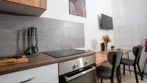 A modern kitchen with a wooden countertop, stainless steel appliances, and a dining area with chairs and a table. - Livemore24 - Apartment 3 in Duisburg 24/7 check-in (Duisburg)