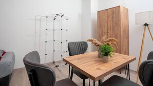 A modern room with a wooden dining table, grey upholstered chairs, a wooden cabinet, and a floor lamp. - Livemore24 - Apartment 3 in Duisburg 24/7 check-in (Duisburg)