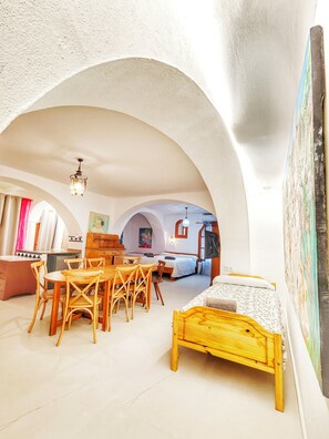 Ein Zimmer mit einem Holzespeisetisch und Stühlen, einem Bett mit Holzrahmen und einem großen Gemälde an der Wand.