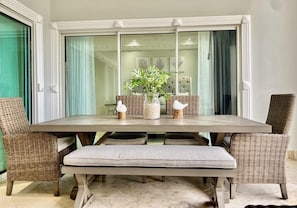 A dining area with a wooden table, wicker chairs, and a bench.