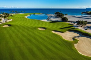 Campo de golf con búnkeres, un obstáculo acuático y vistas al océano.