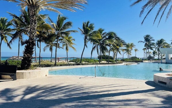 A swimming pool surrounded by palm trees and a clear blue sky.