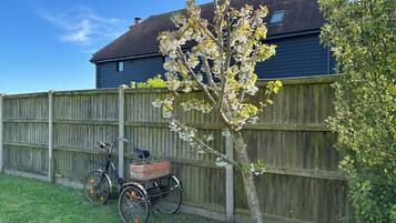 En cykel med en korg och ett träd framför ett trästaket.