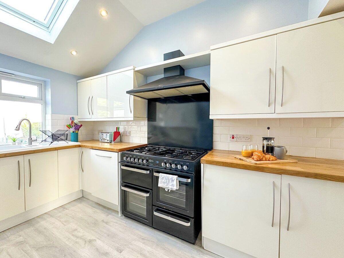 A modern kitchen with a gas stove, oven, and a skylight above.