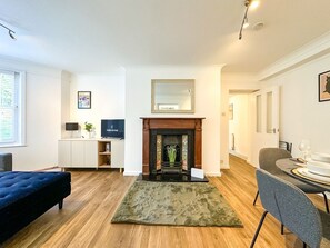 Un salon moderne avec une cheminée, un téléviseur, un canapé et un coin repas avec une table mise pour deux personnes.