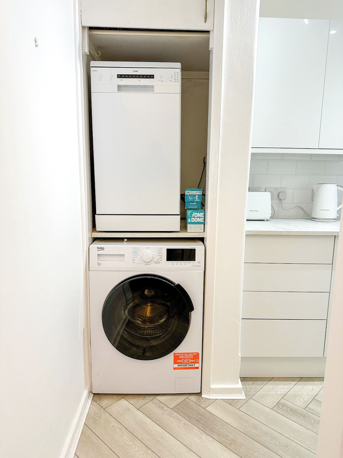 Un espace buanderie compact, avec une machine à laver et un sèche-linge superposés verticalement.