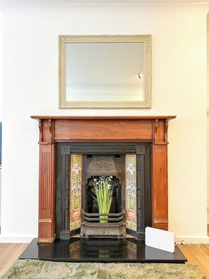 A fireplace with a mirror above it, a decorative vase with flowers, and a laptop on the mantel. - Folkestone Oasis - Spacious Flat - Pets Welcome! (Folkestone)